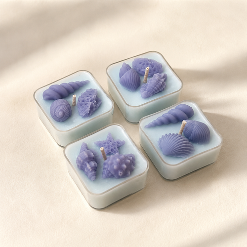 Set of four handmade shell tea lights in soft blue wax with ocean-inspired details, scented in Amalfi Bleu
