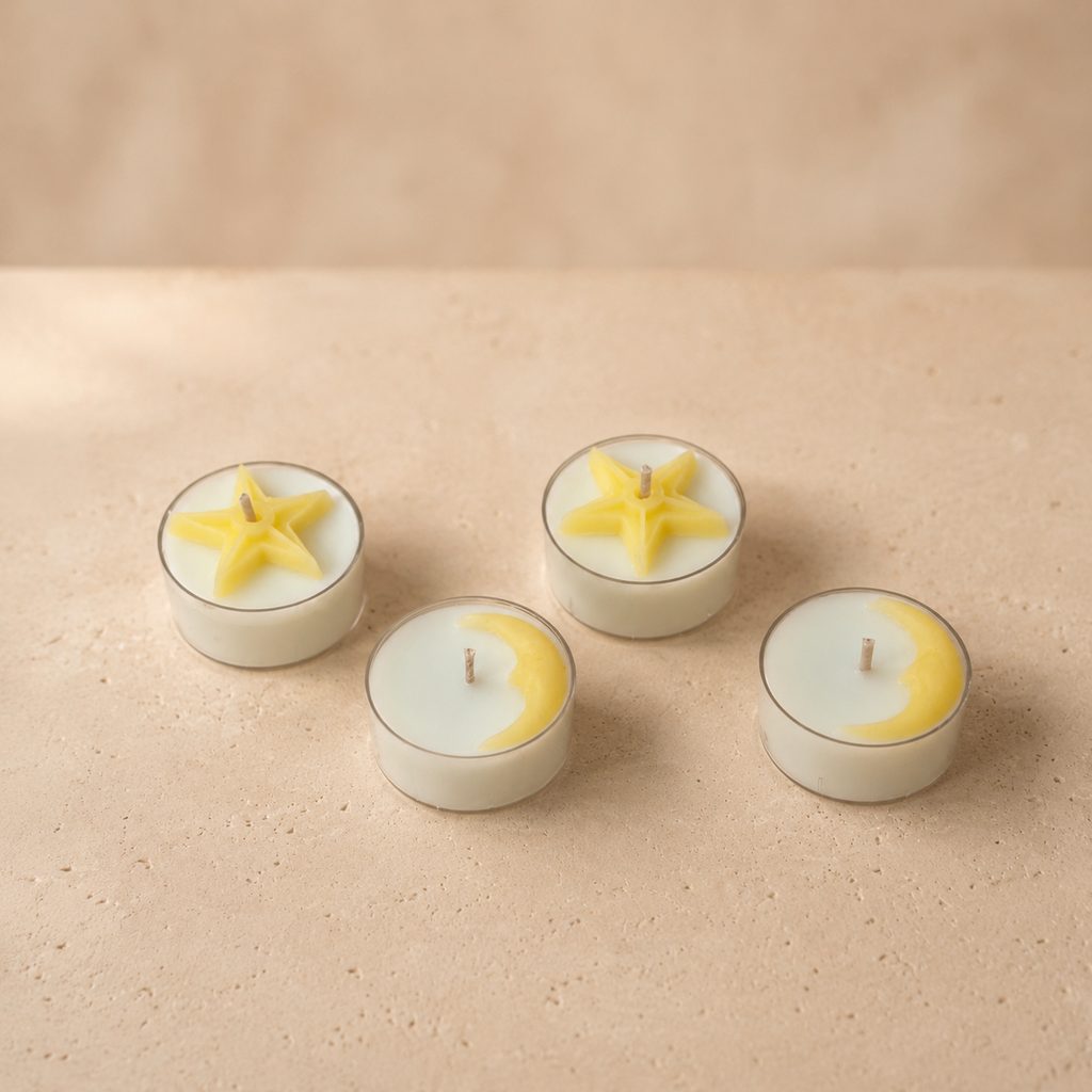 Set of four tea lights with star and crescent moon wax details on a beige stone surface