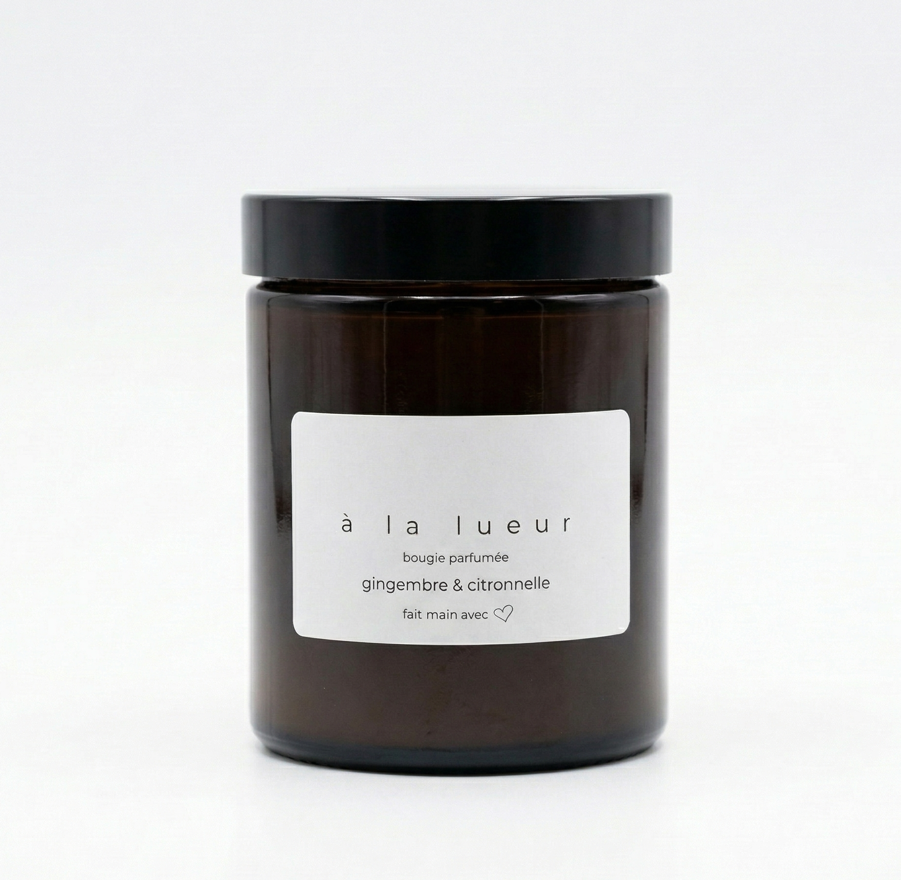 Amber soy candle in amber glass jar with black lid, scented with ginger and lemongrass