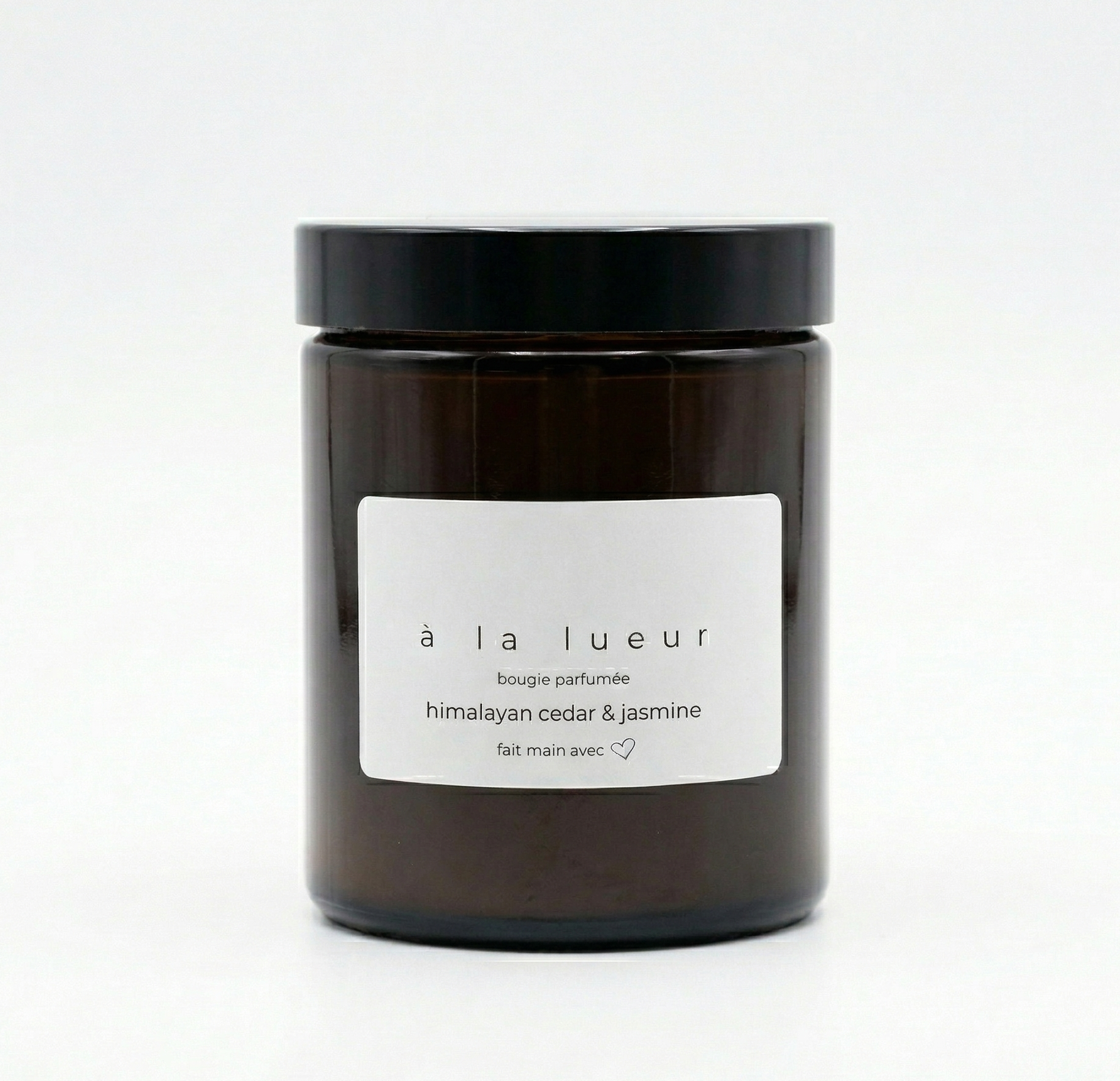 Amber soy candle in amber glass jar with black lid, scented with Himalayan cedar and jasmine